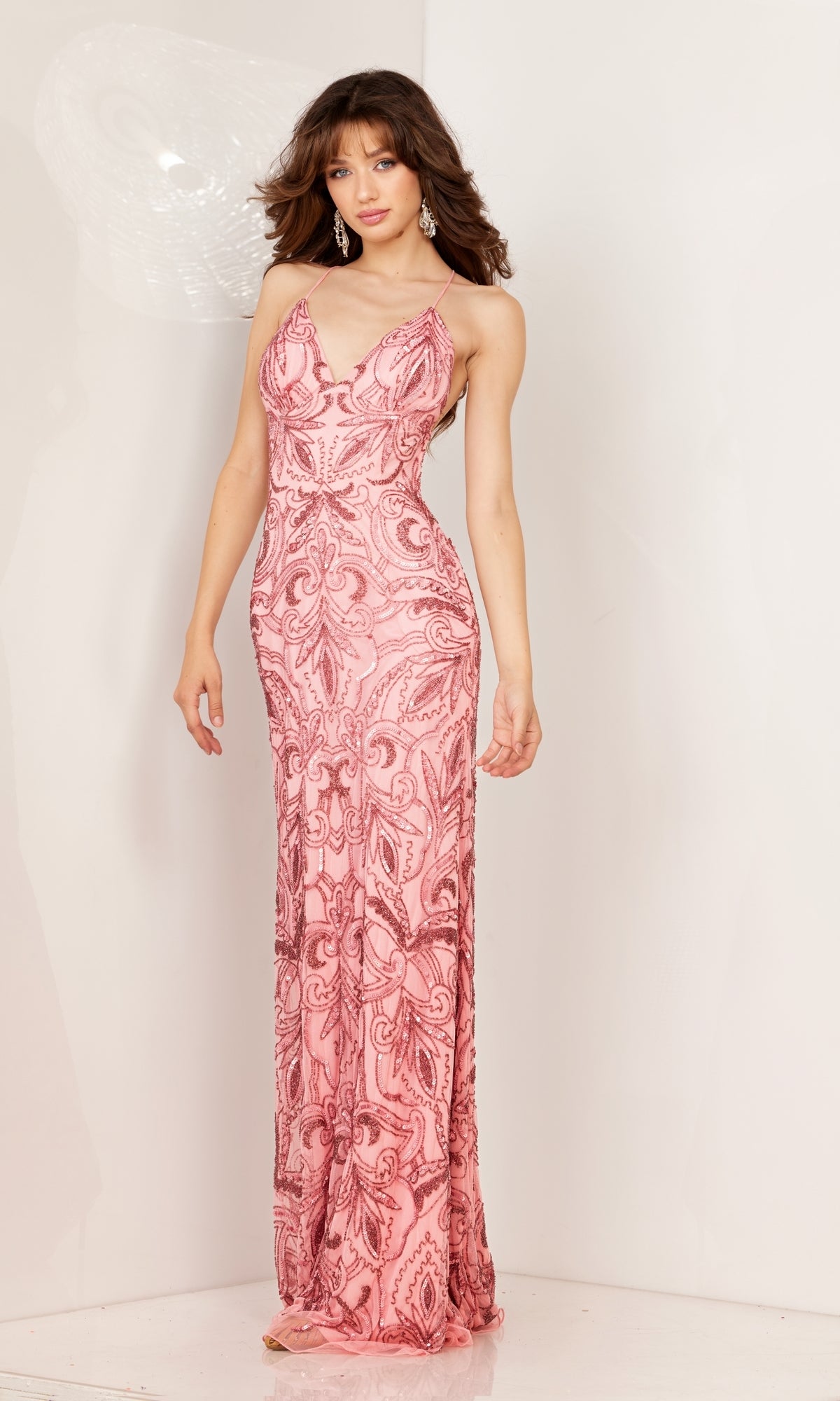 A woman stands facing forward in a Long Sequin-Print Prom Dress with strappy open back, featuring a light pink hue and intricate patterns, sleeveless and floor-length, set against a plain background.